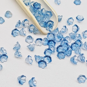 Macro view of blue gradient lily-of-the-valley glass flower beads for DIY jewelry making