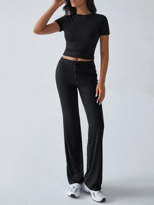 Detail of black short sleeve crop top and drawstring flare trousers on model