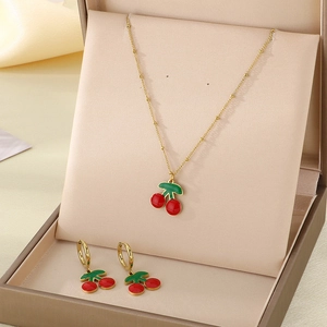 Détail du collier et boucles d'oreilles cerise dans un coffret cadeau de luxe