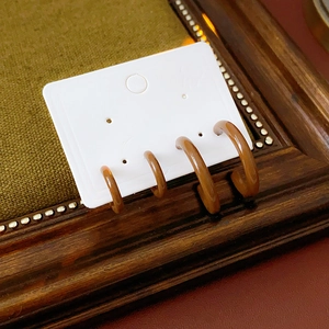 Close-up of caramel C-shaped earrings on a white card inside a vintage wooden frame
