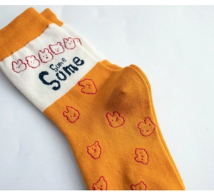 Close-up of orange and cream cotton crew socks with cartoon bear patterns and text
