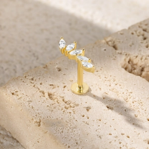 Macro shot of gold S925 silver ear stud with five marquise-cut gems on stone