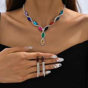 Detail of colorful marquise crystal necklace and red tassel earrings on black fabric