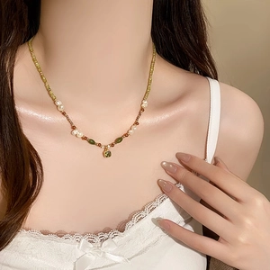 Detail of 18k gold plated necklace featuring green zircon and fresh water pearls