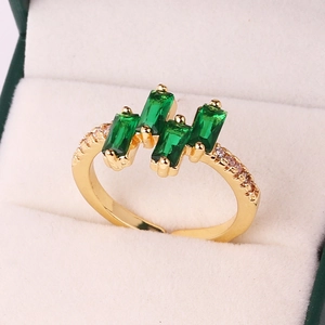 Macro shot of gold-plated ring with four rectangular green zircons and side diamonds