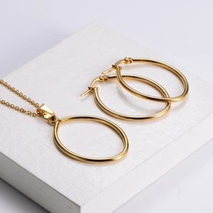 Minimalist gold titanium steel jewelry set featuring oval pendant necklace and hoop earrings