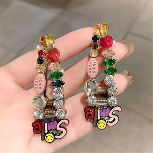 Detail of colorful rhinestone hair clip with Smile charm and handmade pink tag