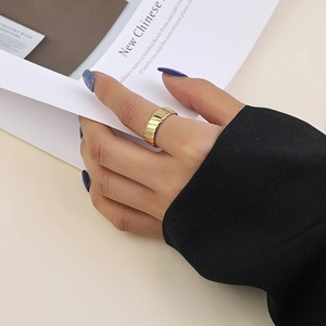 Détail d'une bague large en acier titane doré à nervures sur mannequin avec fond de magazine