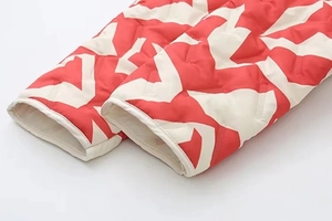 Détail du poignet avec motif géométrique rouge et blanc sur la veste matelassée