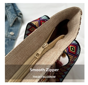 Detailed close-up of smooth metal zipper and colorful ethnic woven handle on tote bag