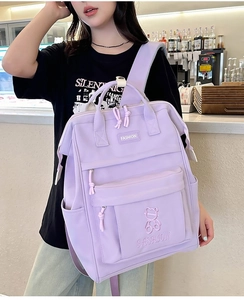 Close-up of a light purple school backpack with bear embroidery in a lifestyle cafe setting