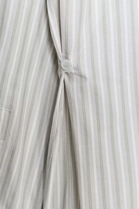 Détail du tissu à rayures verticales gris et blanc avec bouton rond sur une chemise