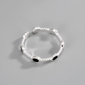 Macro detail of silver twisted band ring featuring elegant black oval enamel accents