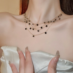 Close-up of triple-layered gold necklace with black gemstones on a model's collarbone