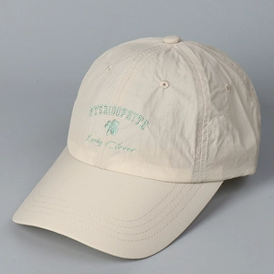 Detail of embroidered green lucky clover and lettering on off-white quick-dry baseball cap