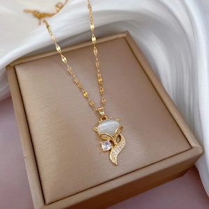 Close-up of a gold fox pendant necklace with cat's eye stone and zircon on silk