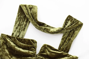 Detailed macro view of olive green velvet dress straps and elegant pleated neckline texture