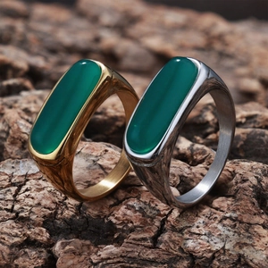 Detailed shot of gold and silver vintage rings with oval green stones on tree bark background