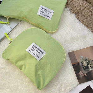 Detail of green waterproof nylon travel storage bags with zippers on white faux fur rug