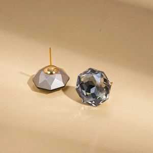 Macro detail of geometric grey crystal earrings with faceted metallic gold backing