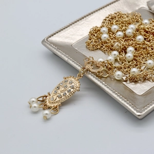Elegant gold pearl forehead chain with tassel drop on a silver display tray