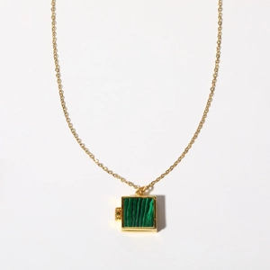 Detail of a square gold locket pendant with malachite texture and side hinge
