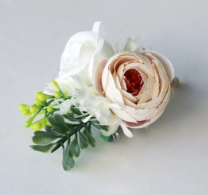 Macro shot of wedding corsage featuring pink buttercup, white rose and green leaves