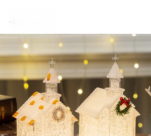 Close-up of lighted Christmas church house figurine with white snow finish and glitter