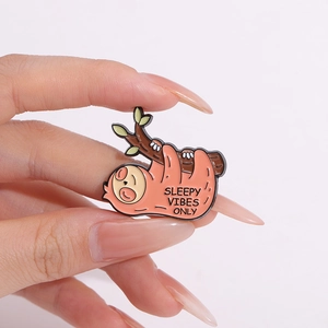 Enamel brooch featuring a cute pink sloth on a branch with Sleepy Vibes Only text