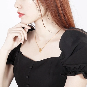 Detailed close-up of a golden Hamsa hand pendant necklace on a woman's neck