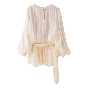 Dettaglio della trama in chiffon a pieghe e della chiusura con laccio su un top color crema