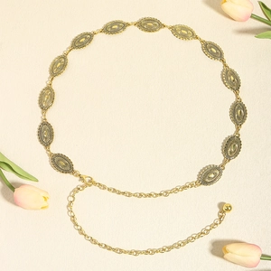 Close-up of vintage matte gold chain belt with engraved oval metal plates and floral decor