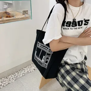Detail view of the black canvas tote bag featuring an artistic white building print
