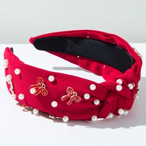 Detail of red knotted headband featuring white pearls and metal bow accessories