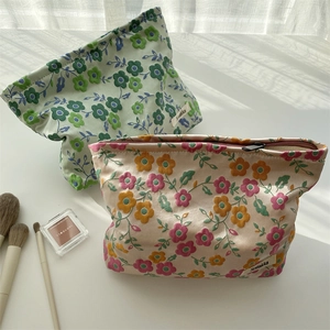 Détail de trousses à maquillage en satin floral avec zips en métal et étiquettes chic