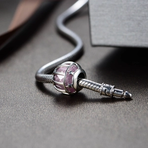 Macro de abalorio de plata S925 con gema rosa y detalle de estrella sobre una pulsera