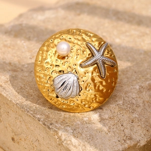 Macro detail of 18K gold plated starfish and pearl ring with hammered metal texture