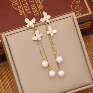 Elegant gold butterfly tassel earrings with white pearls on a vintage jewelry box