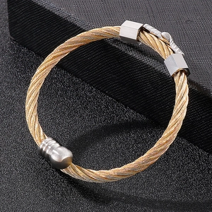 Close-up of gold twisted cable bangle with silver metal connectors on black jewelry display