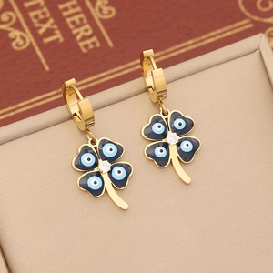 Macro view of gold clover earrings with black enamel blue evil eye and clear gemstone