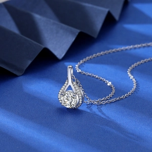 Macro shot of 2ct water-drop pendant necklace with sparkling round zircon on blue fabric