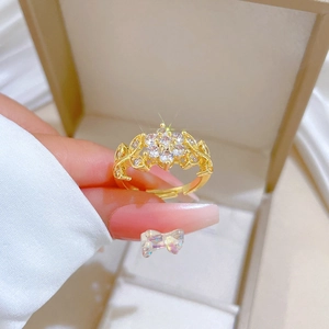 Close-up of golden floral ring featuring leaf design and stones on a jewelry box