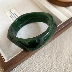 Detailed view of dark green marble resin bangle on a wooden tray with linen lining