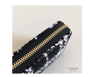 Detailed close-up of black and white tweed fabric with textured gold metal zipper teeth