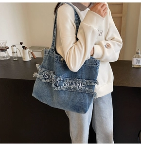 Vue détaillée du sac cabas en denim bleu délavé avec bords effilochés et broderie