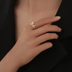 Detail of continuous golden floral pattern ring on model's hand with black suit background