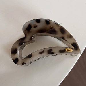 Close-up of tortoise shell heart hair claw clip with golden Love logo engraved on label