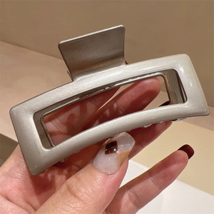 Close-up of a large champagne gold rectangular metal hair claw clip with a polished finish