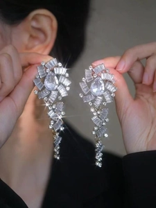 Détail de boucles d'oreilles argentées à pompons en cristal portées par un mannequin