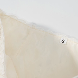Detail of size S label and lace trimming on the inner lining of the beige two-piece set